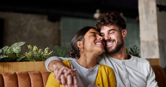 Photo of a young couple cozying up on a couch.